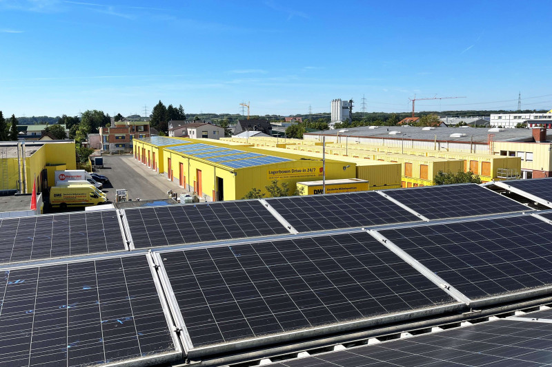 Photovoltaikanlagen auf dem Dach mit Blick auf die gelben Selfstorage‑Lagerhallen des SB‑Lagerhauses und das umliegende Gewerbegebiet bei klarem Himmel.