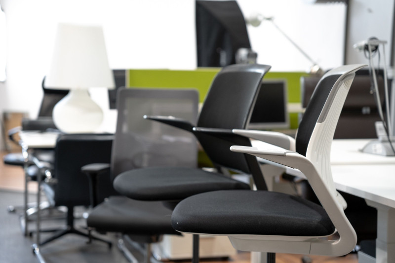 Moderne ergonomische Bürostühle in einem hellen, großzügig eingerichteten Büro mit Schreibtischen und Arbeitslampen.
