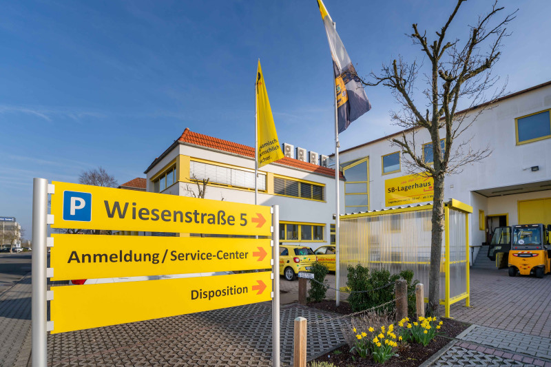 Eingangsbereich des Friedrich‑Friedrich Standorts mit Service‑Center, Disposition und Wegweisern.