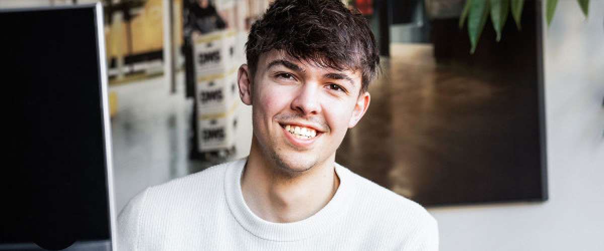 Azubi sitzt am Schreibtisch vor einem Computer und hält einen gelben Marker in der Hand.
