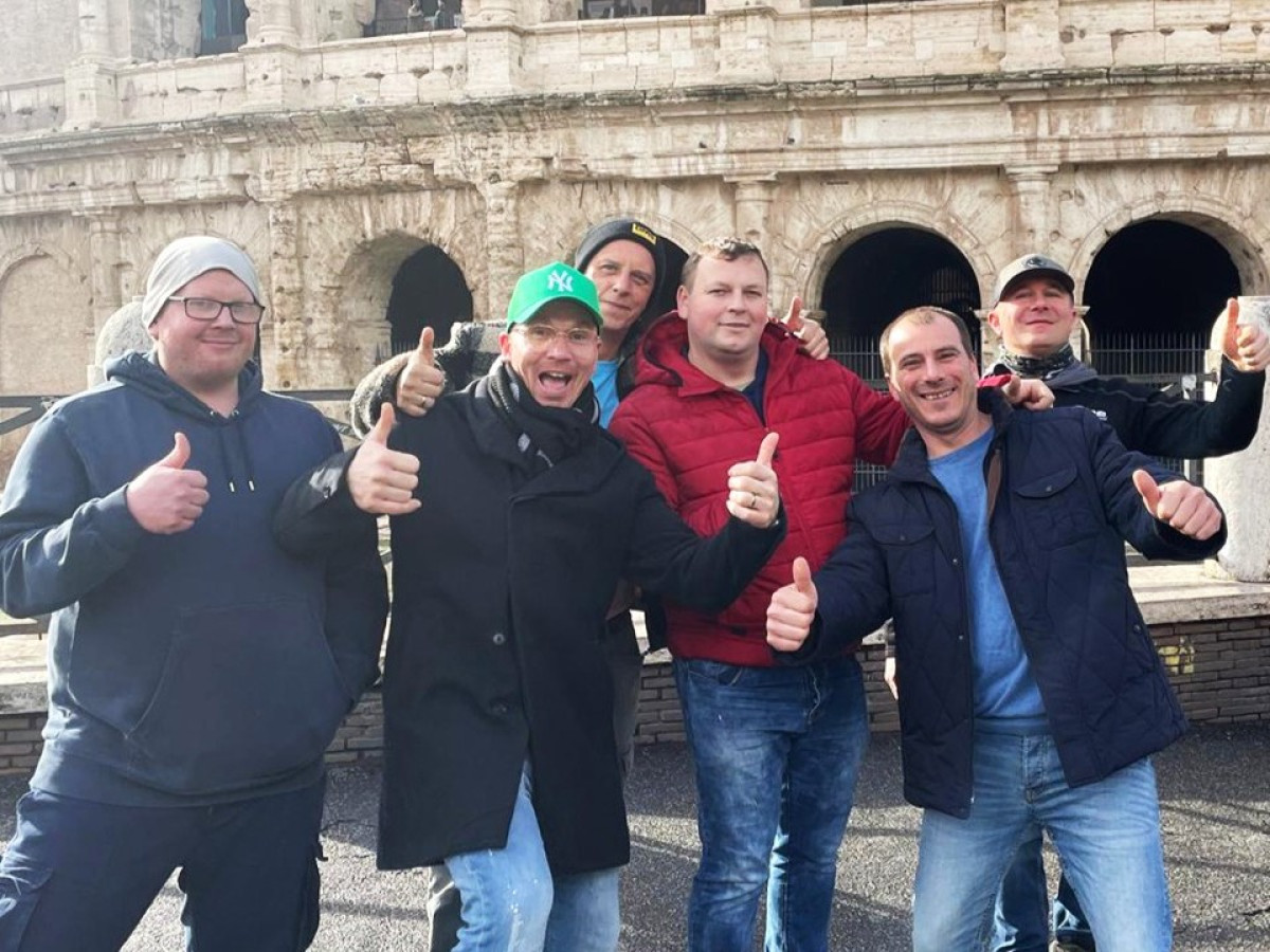 Gruppe von Personen zeigt Daumen-hoch-Geste vor dem Kolosseum in Rom.