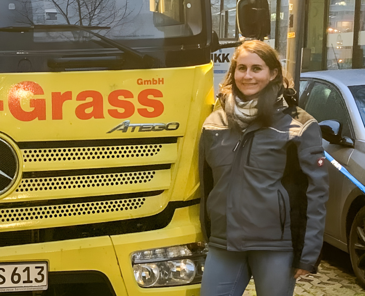 Person in Arbeitskleidung steht vor einem gelben Lkw des Unternehmens Höhne‑Grass.