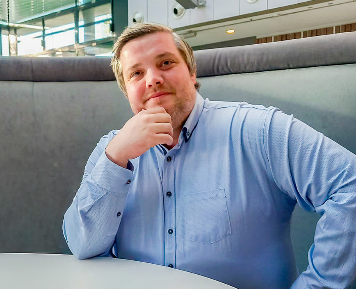 Person in hellblauem Hemd sitzt in einer modernen Lounge‑Sitzgruppe und stützt den Kopf auf die Hand.