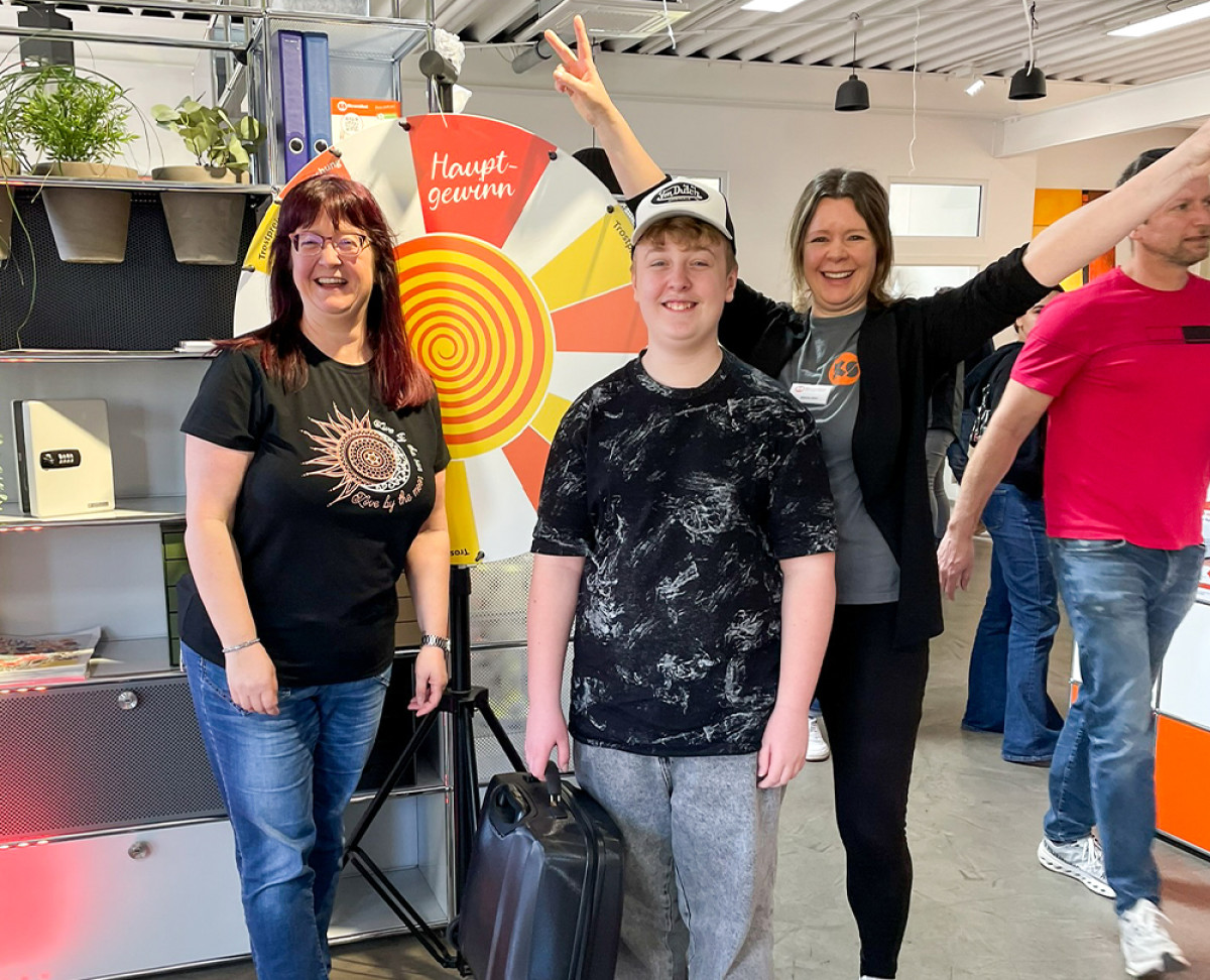 Gewinnspielteilnehmende stehen vor einem Glücksrad mit der Aufschrift ‚Hauptgewinn‘ bei einer Aktion im KS Büromöbel‑Showroom