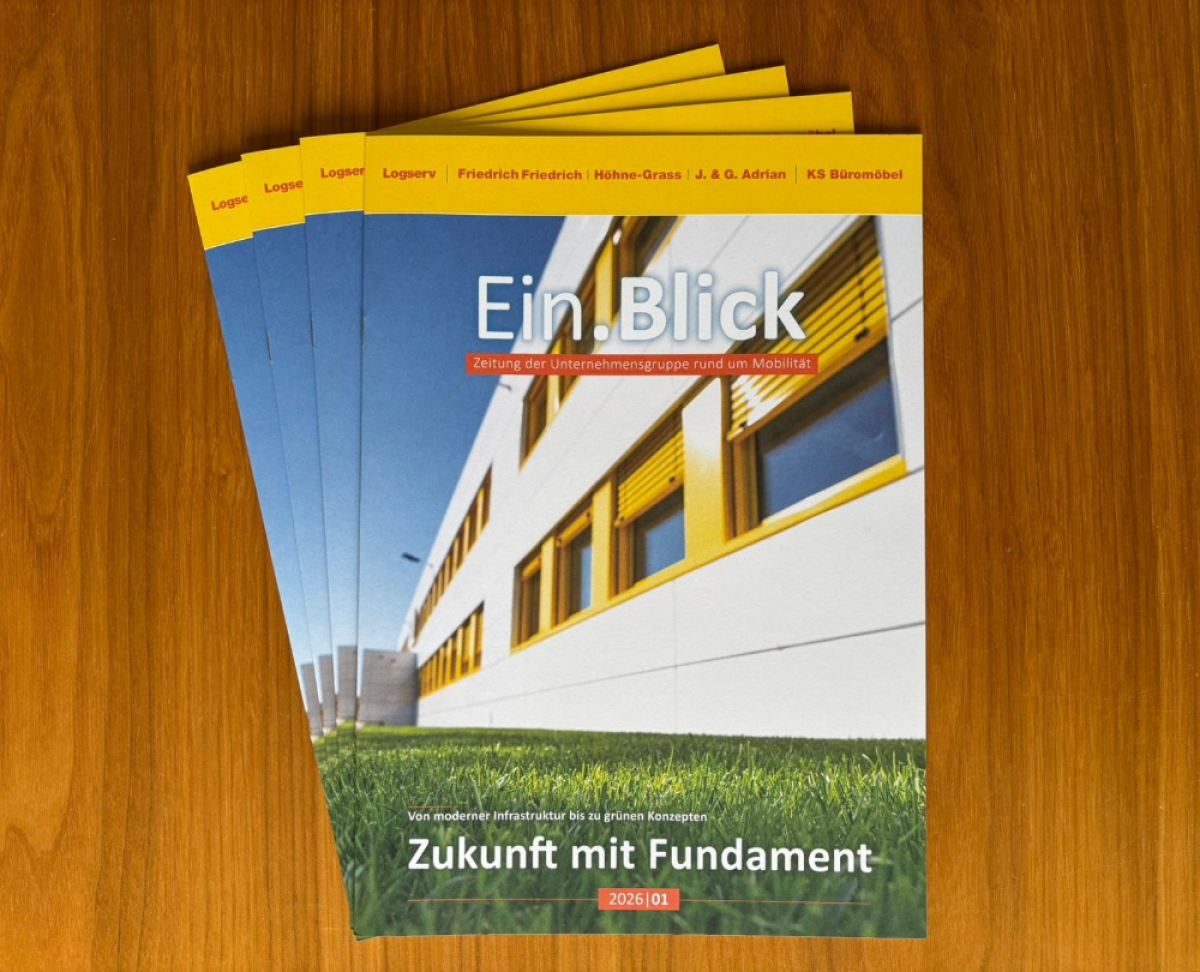 Mehrere Ausgaben der Unternehmenszeitung Ein.Blick auf einem Holztisch