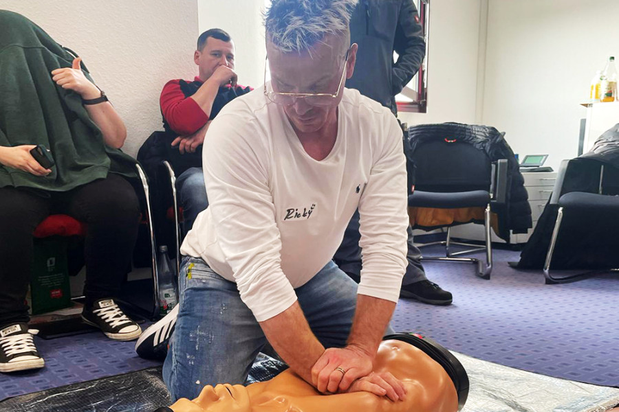 Mann übt Wiederbelebung an einer Reanimationspuppe während eines Erste-Hilfe-Kurses.