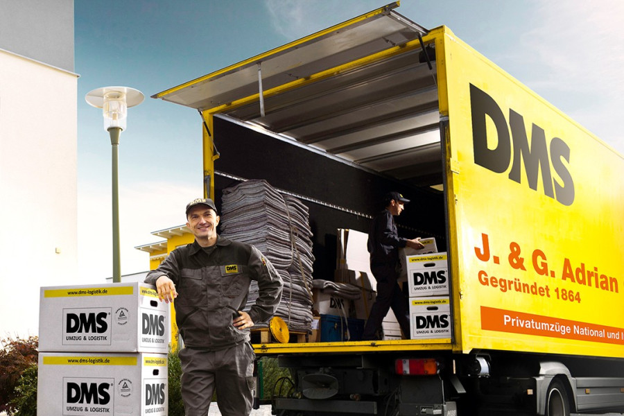 Mitarbeitende eines Umzugsunternehmens laden Umzugskartons in einen gelben DMS‑LKW.