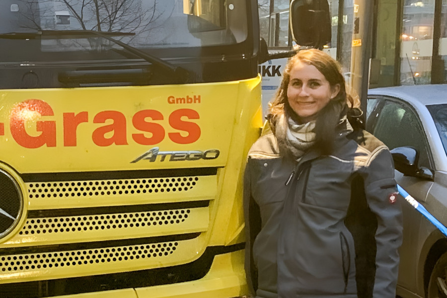 Person in Arbeitskleidung steht vor einem gelben Lkw des Unternehmens Höhne‑Grass.