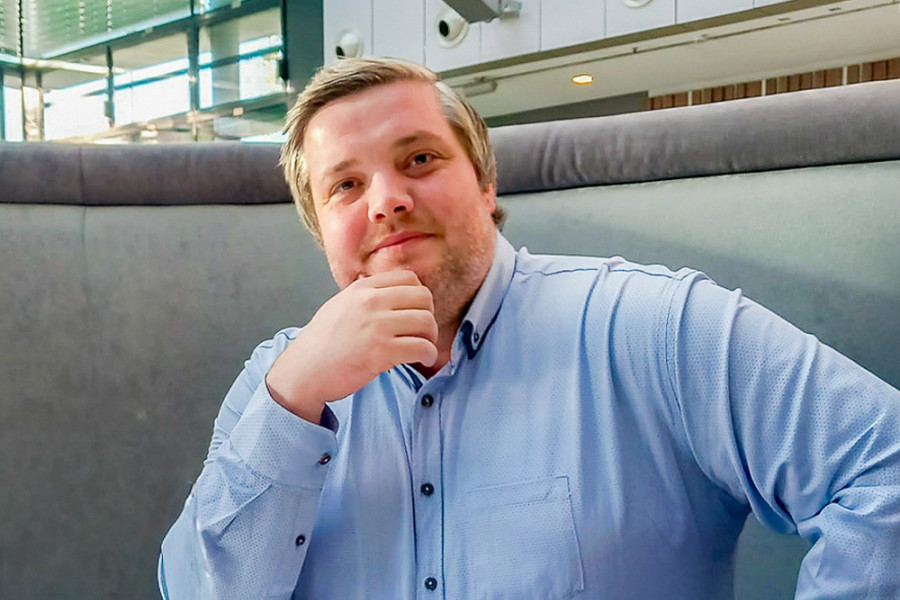 Person in hellblauem Hemd sitzt in einer modernen Lounge‑Sitzgruppe und stützt den Kopf auf die Hand.