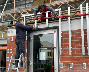 Bauarbeiter arbeiten an der Fassade am Eingang des Gebäudes von Friedrich Friedrich