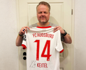 Ralf Feller aus der Geschäftsleitung hält das signierte Trikot von Yannik Keitel 