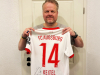 Ralf Feller aus der Geschäftsleitung hält das signierte Trikot von Yannik Keitel 