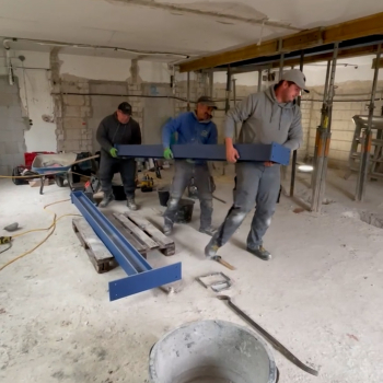 Bauarbeiter tragen zu dritt einen Balken